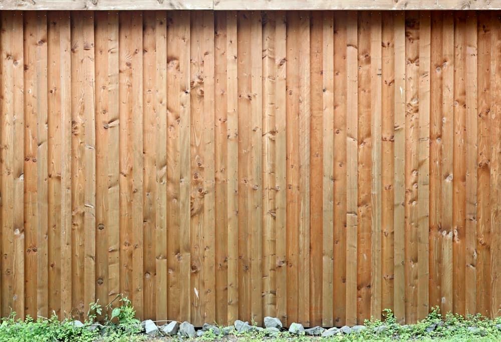 Clôture en lames de bois verticales le long d’un jardin fleuri