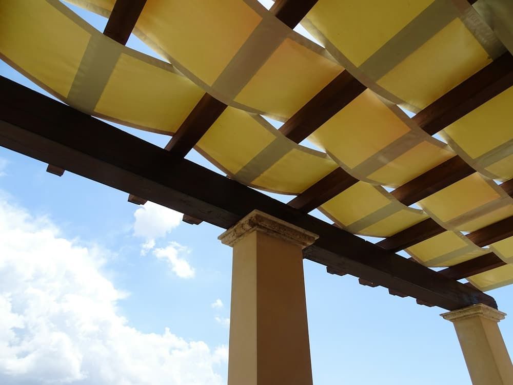 Pergola en bois couverte de bandes de toile jaune