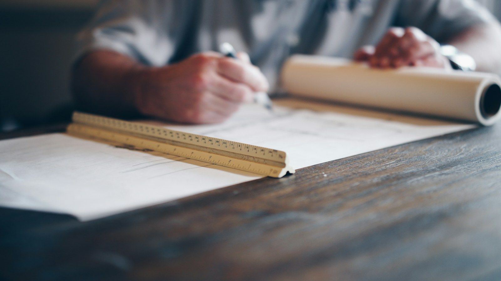Mains annotant des plans avec une règle sur une table