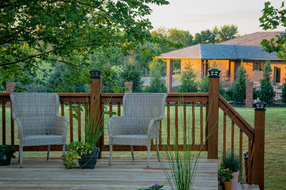 Terrasse en bois surélevée avec garde-corps et fauteuils de jardin